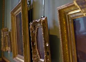 Gallery of ornately framed art hanging at varying heights